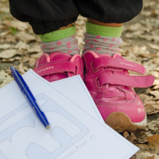 Ein Schreibblog mit Stift liegt an Kinderschuhen