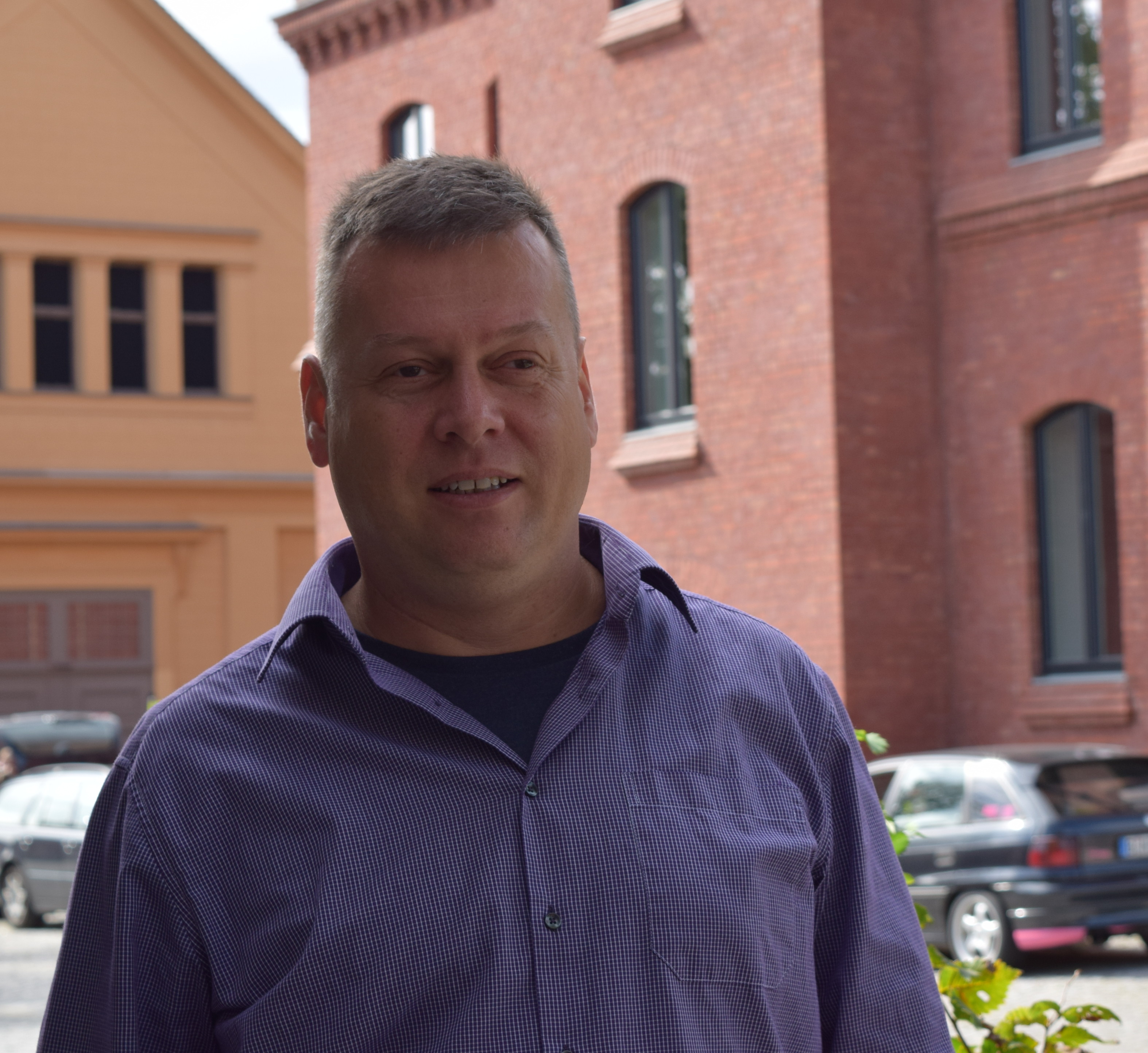 Stadtverordneter Uwe Fröhlich (Bündnis 90/ Die Grünen) steht vor einem roten Backsteingebäude und berichtet über Fairtrade-Towns. Foto: Lilith Grull