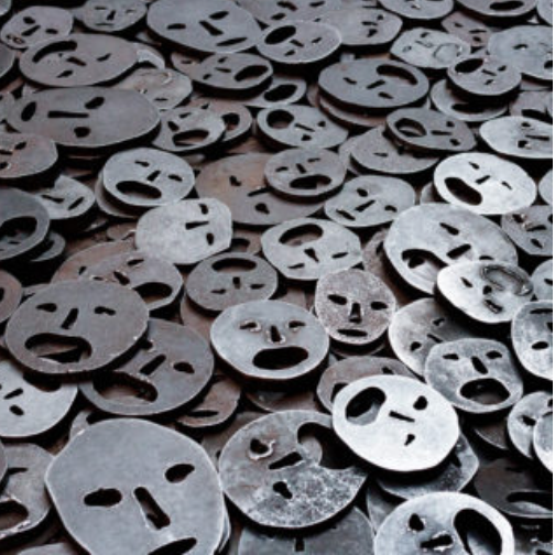 Eine Reihe von metallischen Gesichtern, 2 dimensional und entfremdet, wie Münzen auf dem Boden verteilt.