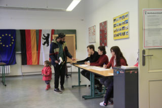 Mann gibt Stimmzettel im Wahllokal ab.