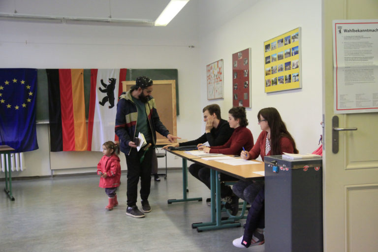 Mann gibt Stimmzettel im Wahllokal ab.