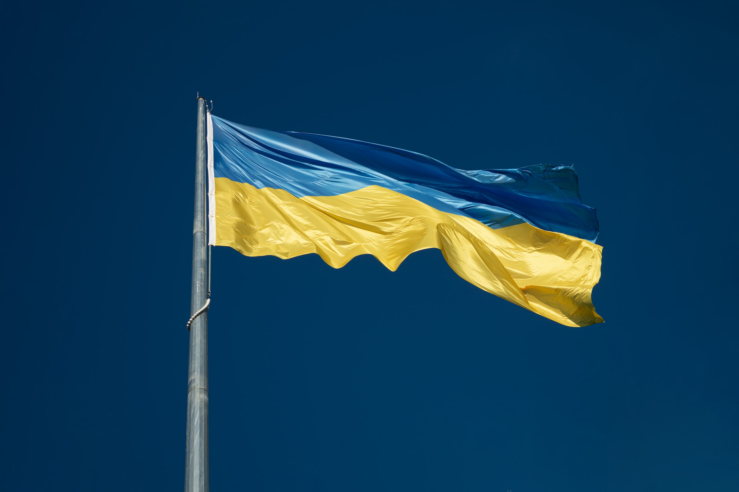 Eine ukrainische Flagge weht am tiefblauen Himmel.