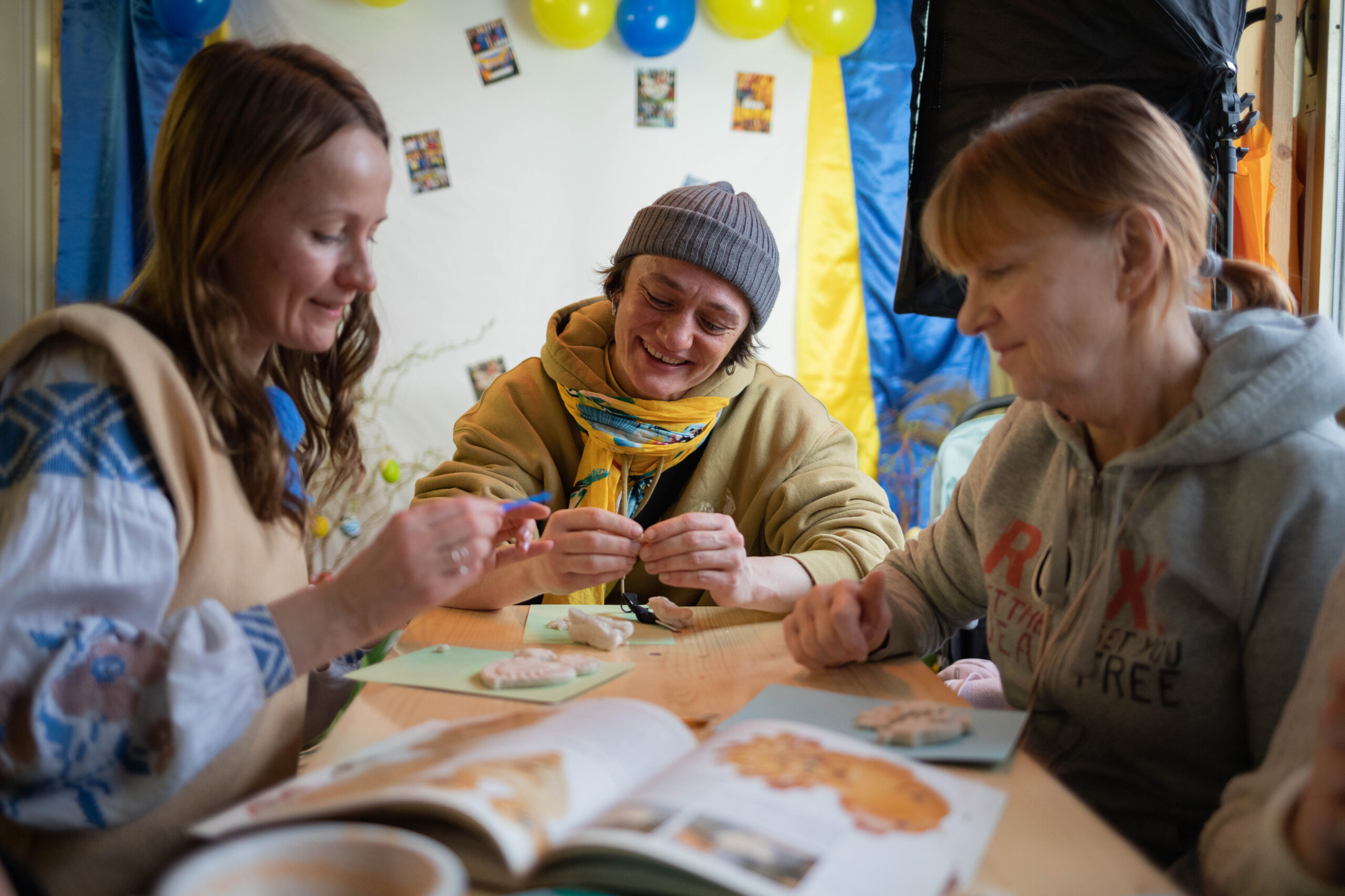 Es sind drei Frauen zu erkennen, die gemeinsam basteln und lächeln.