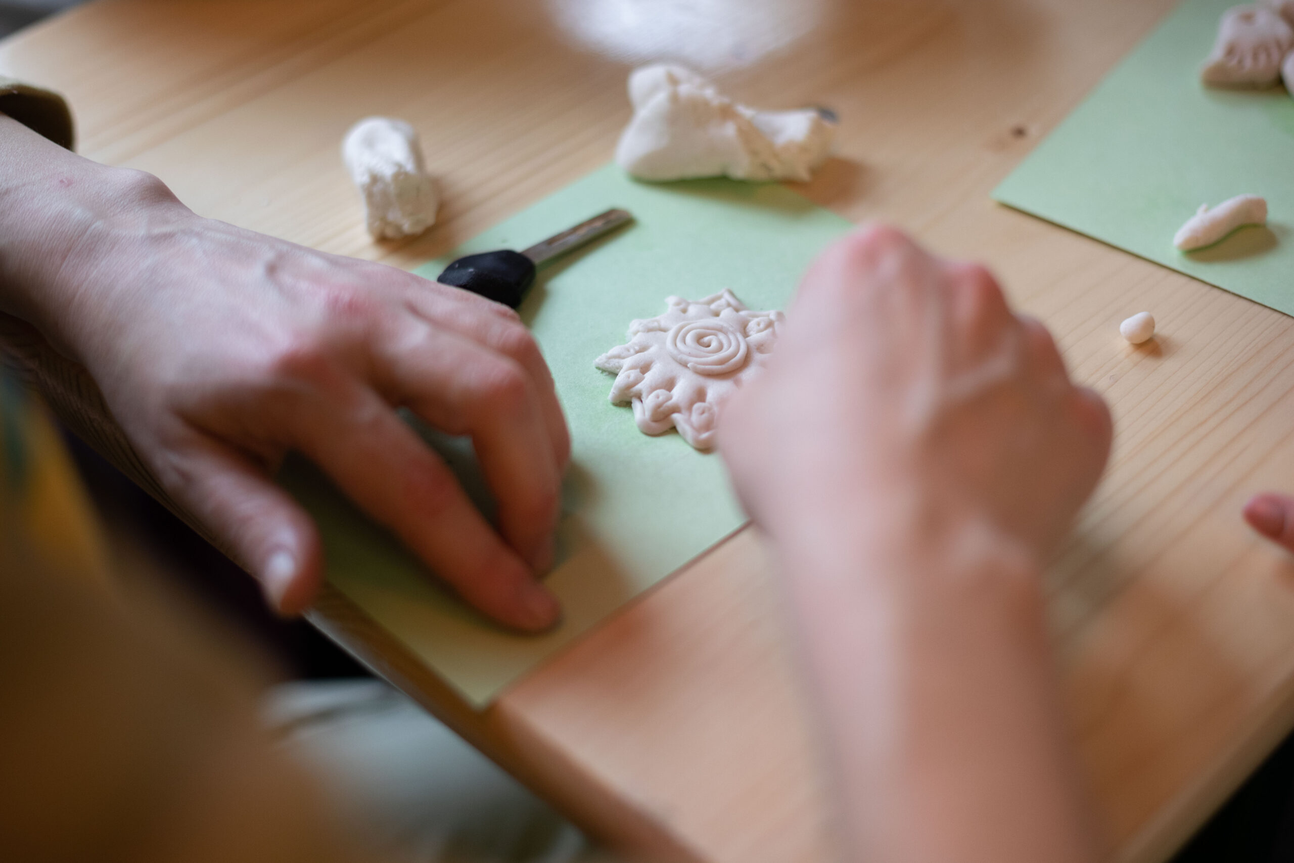 Es sind Hände zu erkennen, die eine Blume aus Salzknete basteln.