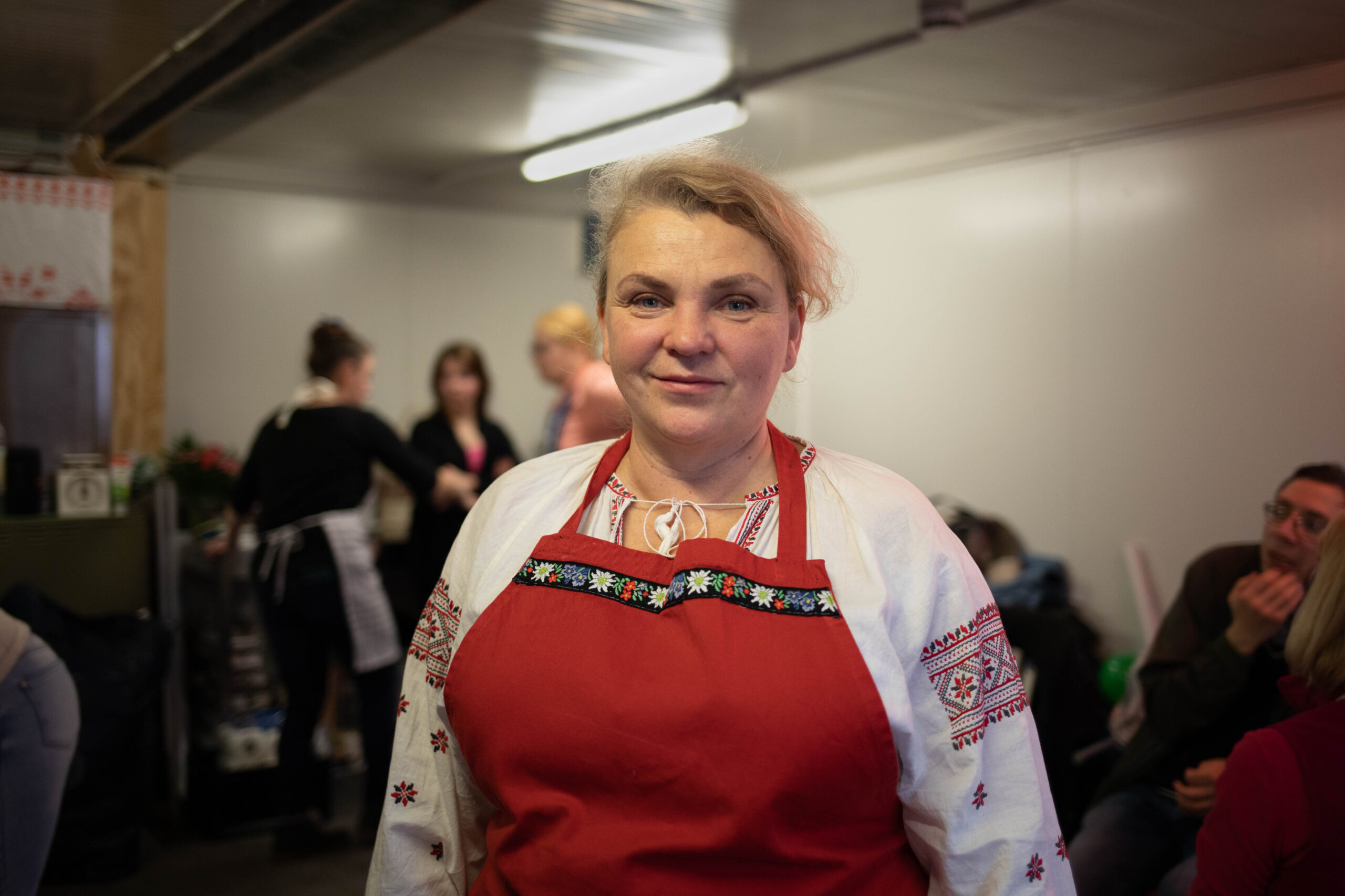 Es ist eine Frau in einer roten Schürze zu erkennen.