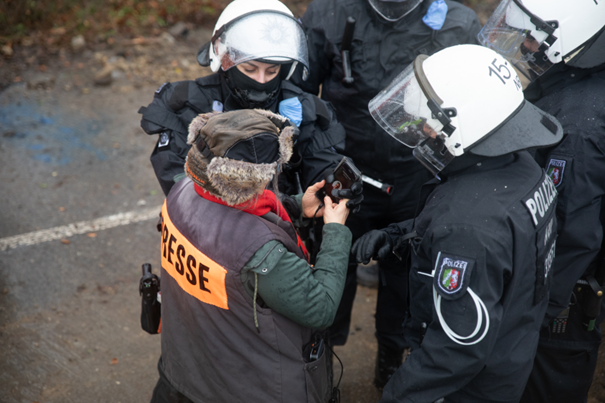 Ein*e Polizist*in entwendet einem*r Journalist*in ihr Telefon beim Versuch Jörg Reichel vom Journalist*innenverband zu erreichen.