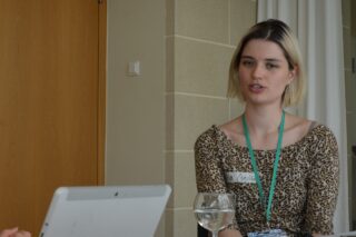 Elisa Habermann sitzt an einem Tisch und spricht.